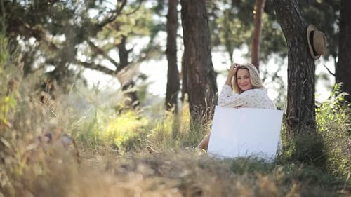 Woman with Wavy Hair Sitting By Trees