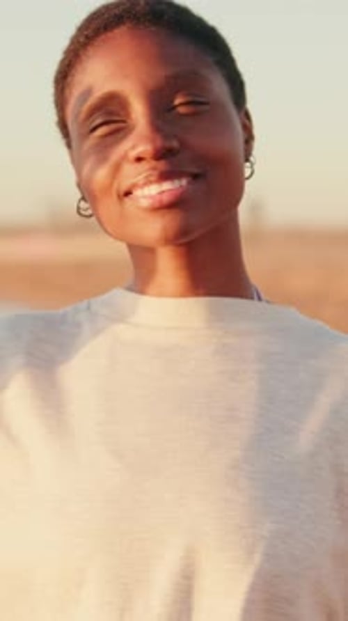 Jeune fille souriante regardant le soleil, accueillant l'aube d'été sur la plage