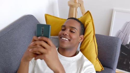 Young Man Relaxing at Home Using Cell Phone
