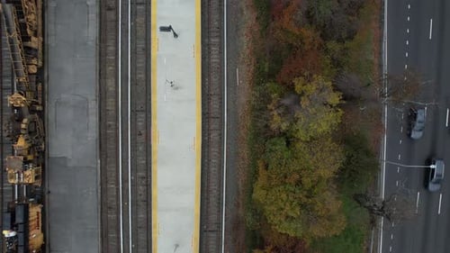 A top down view of a train station with a construction train on the track. There are autumn colored