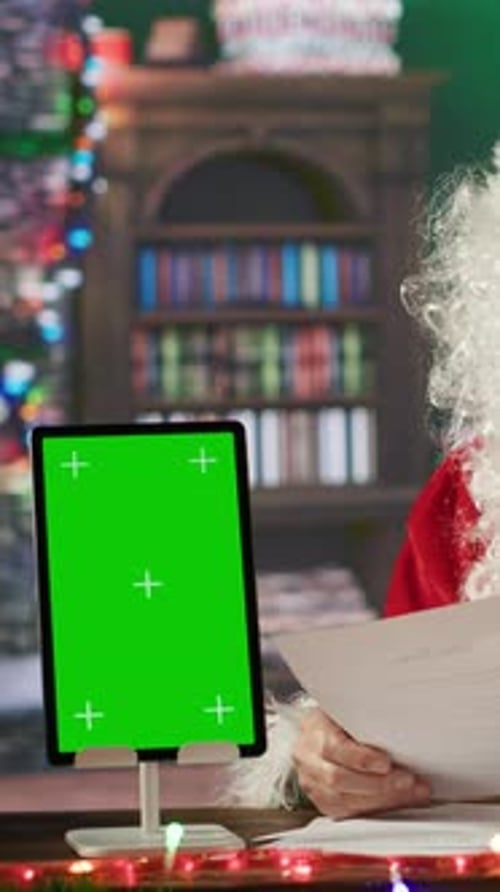 Vertical Video Father Christmas Reads Letters with Wishes Next to Green Screen on Device