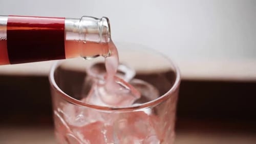 Pouring Pink Drink into Glass Filled with Ice