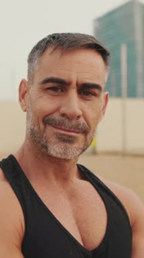 Mature smiling man looking at the camera while standing on the beach