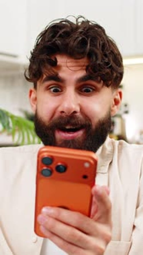 Man Using Smartphone Reacts to Good News Indoors
