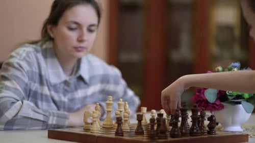 Woman and Child Playing Chess Game at Home