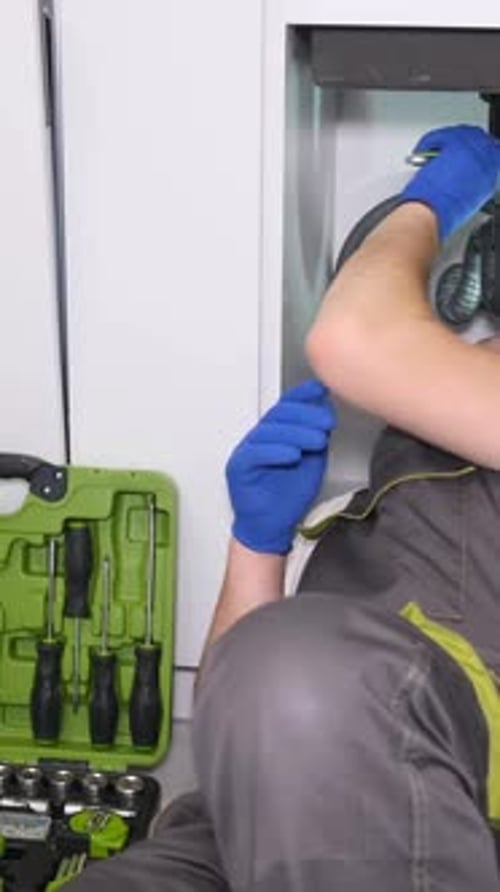 A Plumber in Protective Work Clothes and Gloves is Doing Plumbing Work Vertical Video