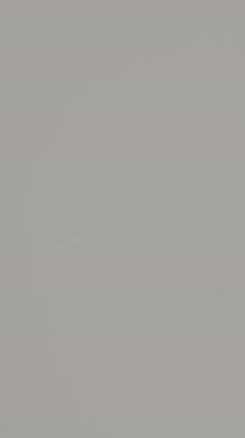 Vertical video. Squeezing a tube of glue with golden glitter onto the glass, close-up view.