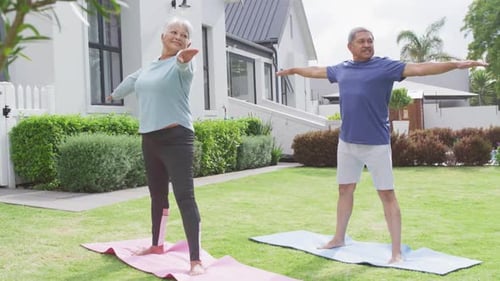 Happy senior diverse couple practicing yoga in garden