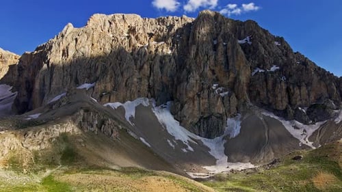 A mountain with snow on it and a green valley below