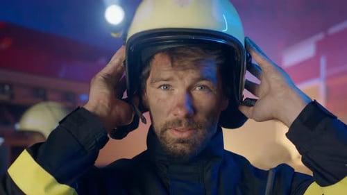 Close Up of Mature Dirty Firefighter Putting on Helmet with Fire Truck