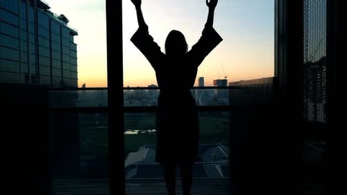 Silhouette of Woman in Bathrobe Stretching Arms on Terrace, Super