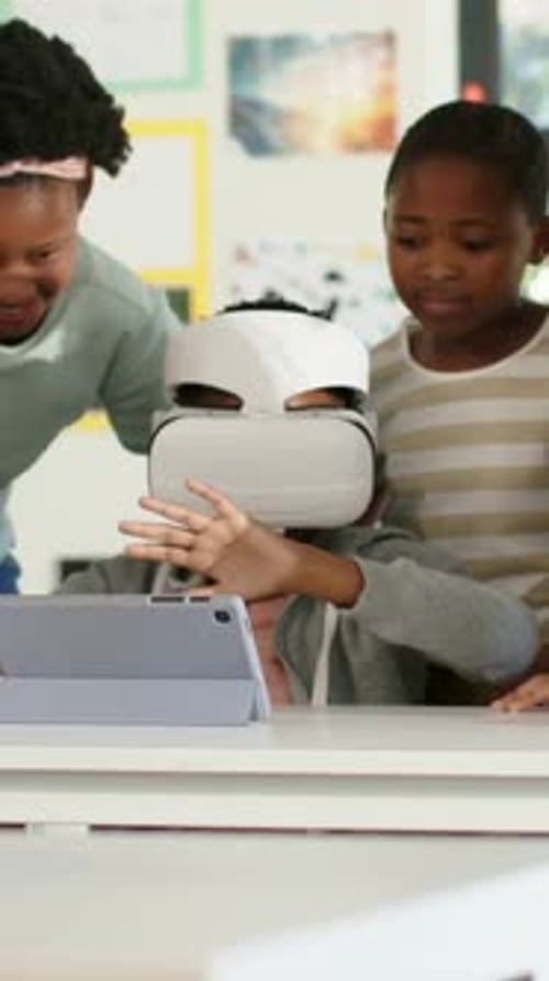 Vertical video: Leaning peers urging seated youth in hoodie tapping tablet with white VR in class