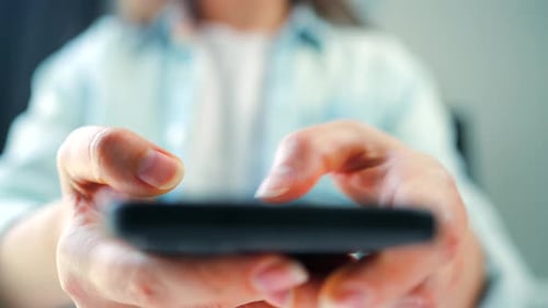 Frau scrollt auf dem Smartphone in Nahaufnahme durch Social-Media-Feeds