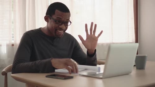 Man at Table Video Calling on Laptop