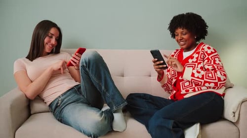 Two women relaxing on couch with phones
