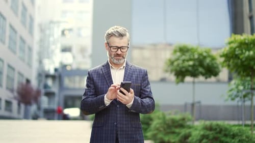 Man Using Phone in Front of Office Building