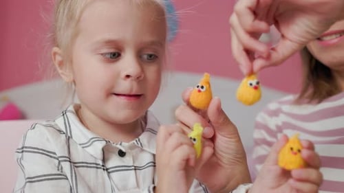 Little Girl Plays with Knitted Toy Chicken with Adult