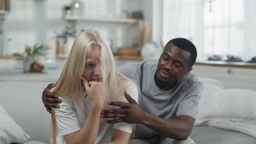 Man Comforts Crying Woman on Sofa Indoors