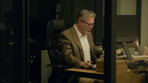 Fatigued Male Analyst Dozing Off in front of Computer at Midnight