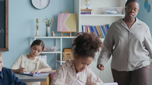 Teacher Helping Elementary School Students in Classroom