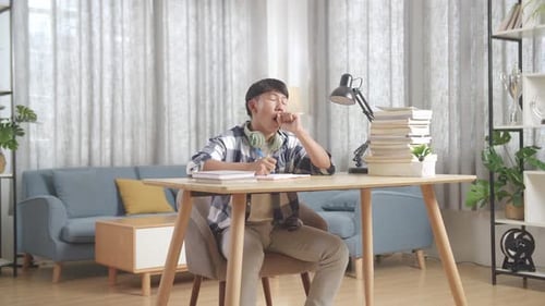 Tired Asian Teenager Yawning And Sleep On The Table At Home After Doing Home Work