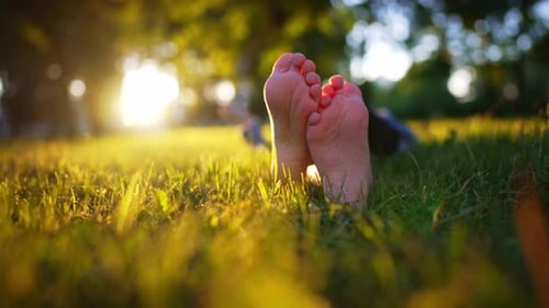 Nackte Füße eines Kindes im grünen Gras eines sonnigen Parks im Sommer