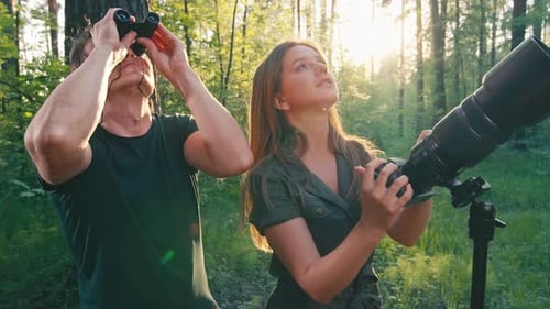 Observation des
oiseaux dans le parc. Couple observe les oiseaux avec des jumelles et un appareil photo avec téléobjectif. Oiseau amateur