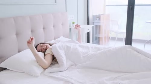 Attractive Woman Waking and Stretching in Modern Bedroom