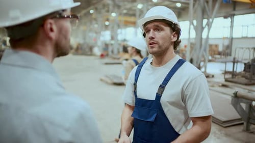 Factory Worker Giving Handshake and Talking to Engineer in Industrial Warehouse