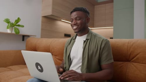 Smiling Man Video Calling on Laptop at Home