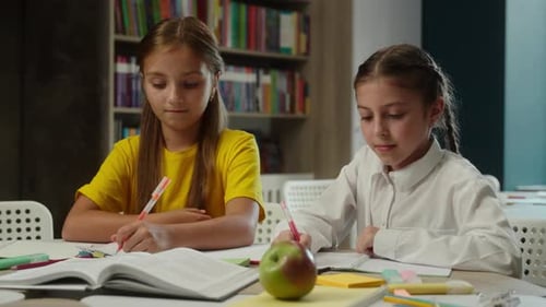 Two Focused Girls Studying and Writing at School
