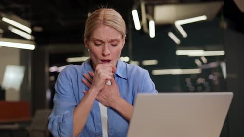 Woman Coughing in an Office with Laptop