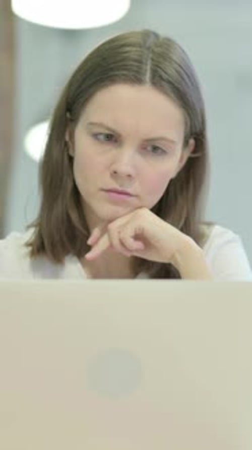 Thoughtful Woman Working on Laptop in Office