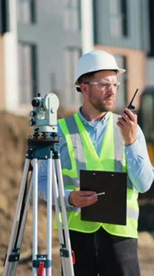 Surveyor Engineer Coordinating on Construction Site with Walkie Talkie