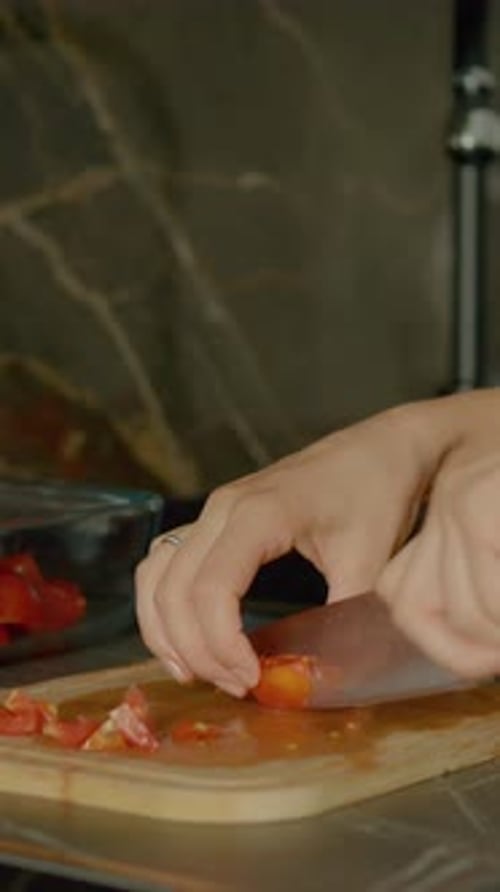Woman Cuts Tomato on Wood Cutting Board