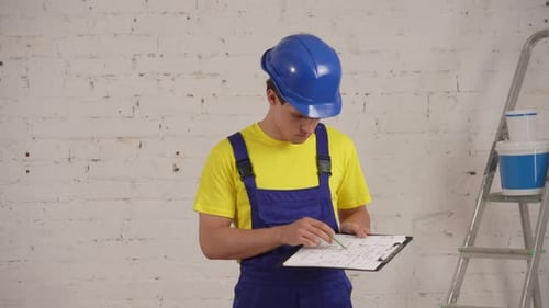 Focused Builder Examining Blueprint in Home