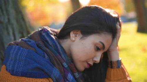 Girl thinking in a park. Lost in her thoughts
