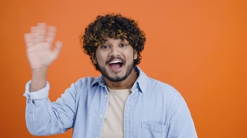 Fröhlicher Hindu-Mann mit versauten Haaren winkt Hallo in die Kamera