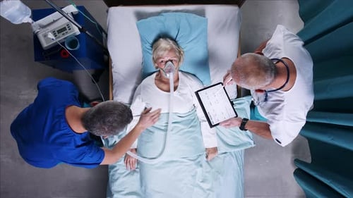 Top View Of Doctors With Stethoscope Examining Patient In Bed In Hospital. Copy Space.