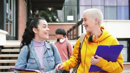 a Group of Two Young Female Students Walking and Talking About Gossip Having Fun at the University
