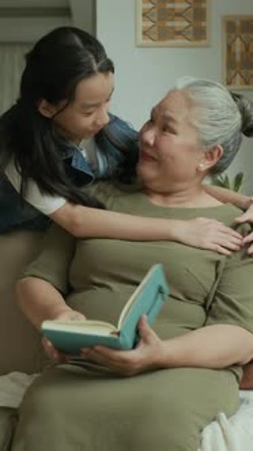 Loving Granddaughter Embraces Grandmother Reading Book