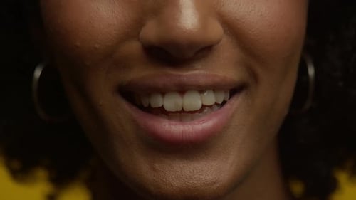 Closeup of Smiling Woman Showing Teeth with a Yellow Background