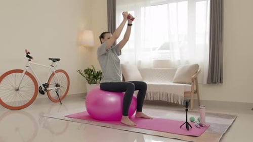 Woman Exercising with Weights on Exercise Ball at Home