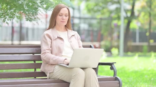 Woman Works on Laptop in Green Urban Park
