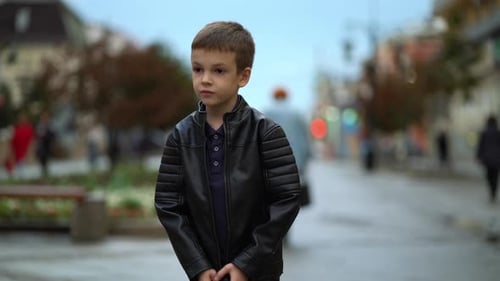 The Child Fastens the Lock of the Jacket on the City Street