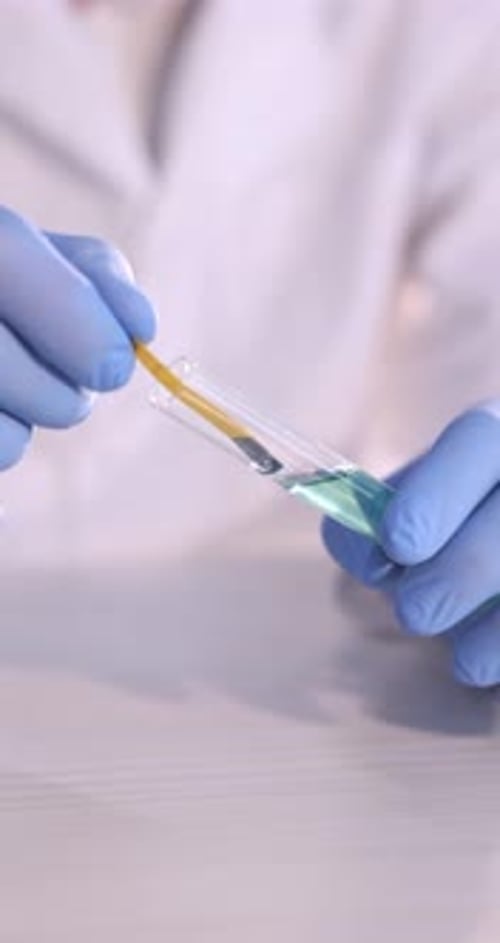 Employé de laboratoire prélevant un échantillon avec une bandelette de test de pH au bureau, gros plan