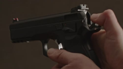 Thumb pulling back hammer of pistol and shooting - close