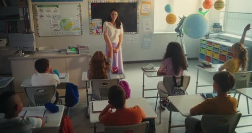 Primary School Children Raising Hands Female Teacher Calling Boy and Girl to the Board