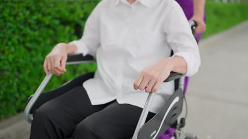 Wheelchair and elderly care in garden for outdoor walk in retirement. Female caregiver smile and tal