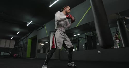 Adult Man Training with Punching Bag in Gym